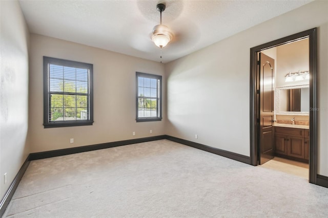 spare room featuring light carpet, plenty of natural light, and baseboards