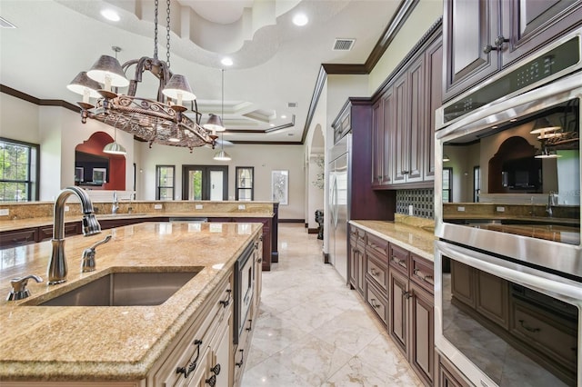 kitchen featuring visible vents, ornamental molding, a sink, stainless steel appliances, and light stone countertops