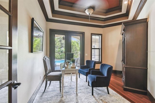 living area featuring baseboards, a tray ceiling, ornamental molding, french doors, and wood finished floors