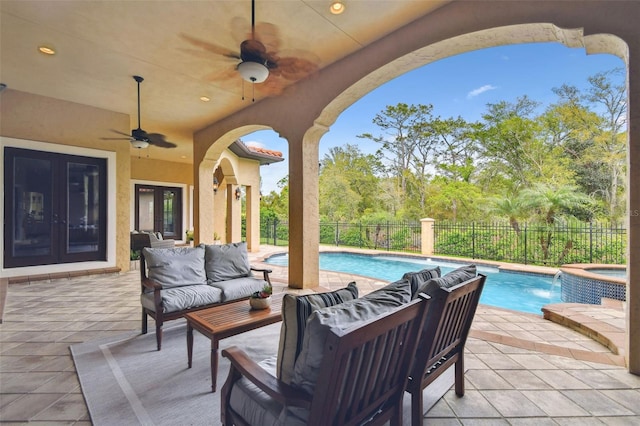 view of patio featuring a ceiling fan, a pool with connected hot tub, an outdoor living space, a fenced backyard, and french doors