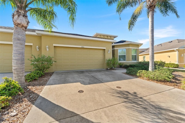 view of front of property featuring concrete driveway, an attached garage, and stucco siding
