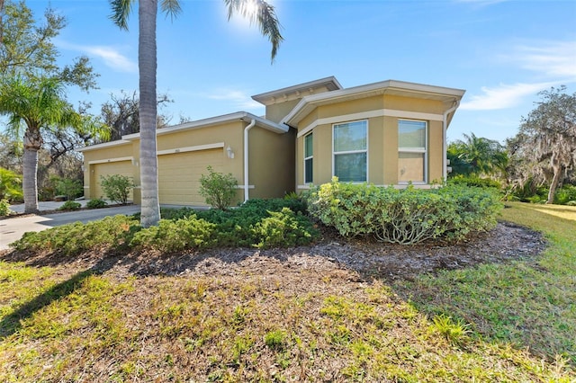 view of front of home with stucco siding, driveway, and an attached garage