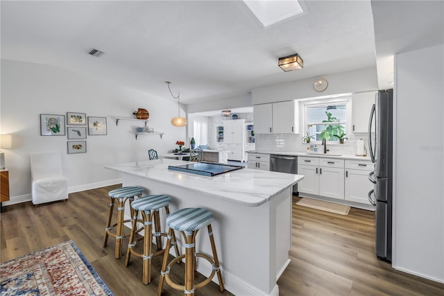 kitchen featuring a sink, a breakfast bar area, appliances with stainless steel finishes, visible vents, and decorative backsplash