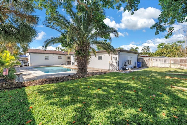 back of house featuring stucco siding, fence, a patio, a fenced in pool, and a lawn