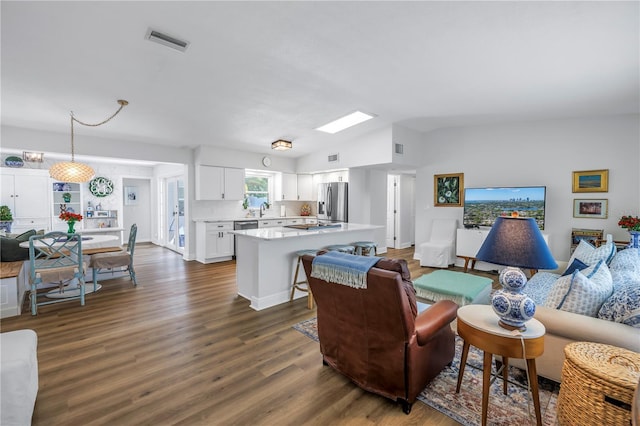 living area with dark wood-style floors, visible vents, and lofted ceiling