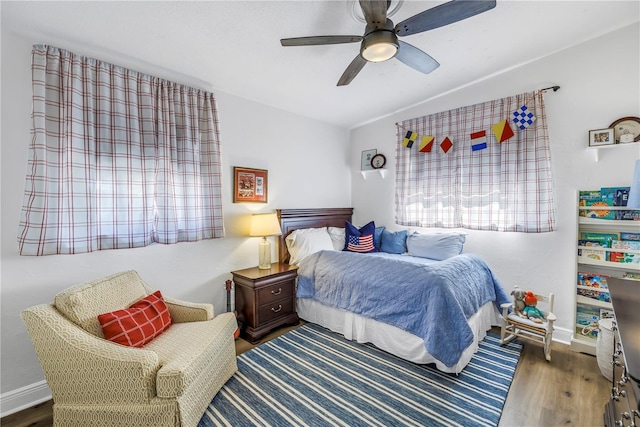 bedroom featuring baseboards, wood finished floors, and a ceiling fan