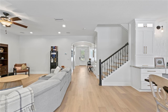 living room with light wood-type flooring, visible vents, a ceiling fan, recessed lighting, and arched walkways