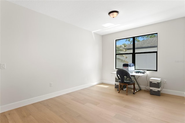 unfurnished office with baseboards and light wood finished floors