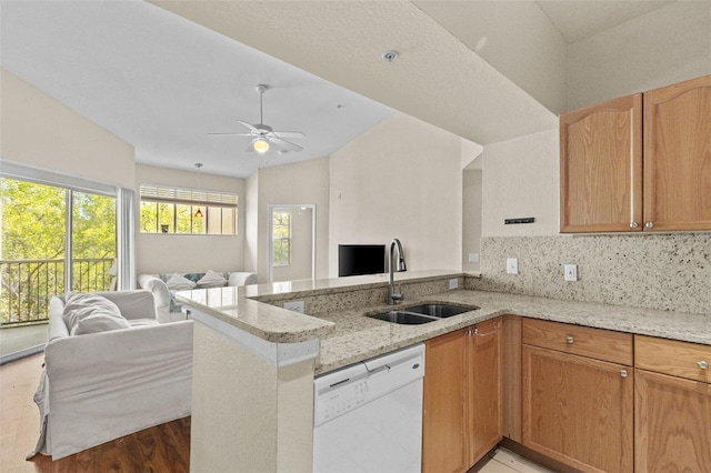 kitchen featuring a sink, open floor plan, a peninsula, light stone countertops, and dishwasher