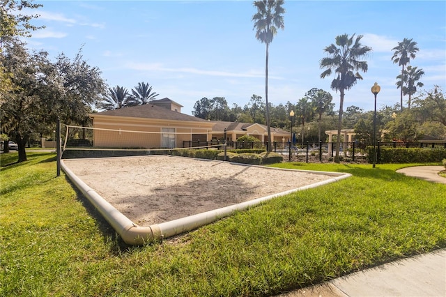 view of community featuring volleyball court, a lawn, and fence