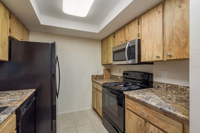 9860 62nd Ter N Unit 1051, Saint Petersburg, FL 33708 - kitchen with baseboards, dark stone counters, a tray ceiling, black appliances, and light tile patterned floors