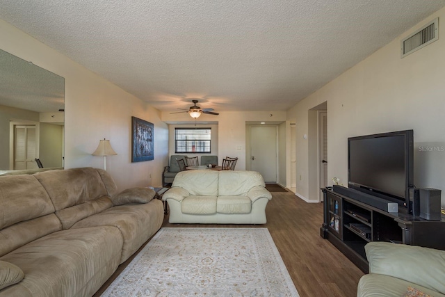 9860 62nd Ter N Unit 1051, Saint Petersburg, FL 33708 - living room featuring baseboards, a textured ceiling, dark wood-style floors, visible vents, and a ceiling fan