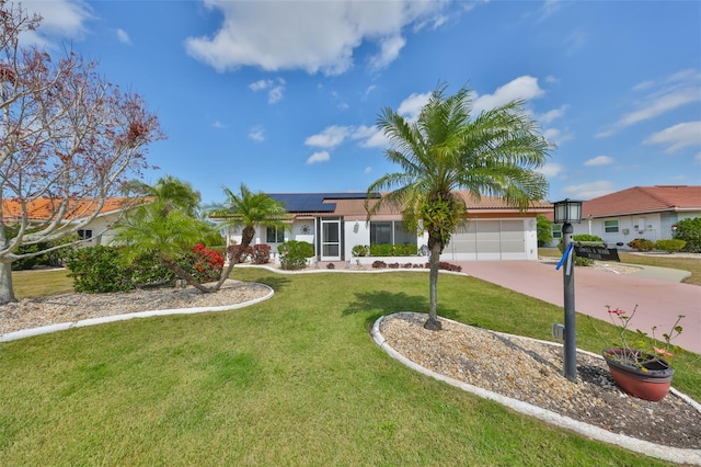 ranch-style home with a garage, roof mounted solar panels, a front lawn, and driveway