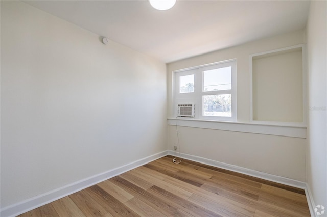empty room with baseboards, light wood-style flooring, and cooling unit