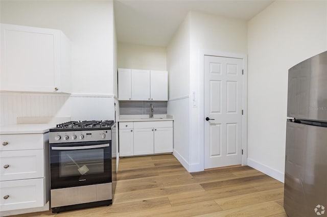 kitchen featuring white cabinetry, a sink, stainless steel appliances, and light wood finished floors
