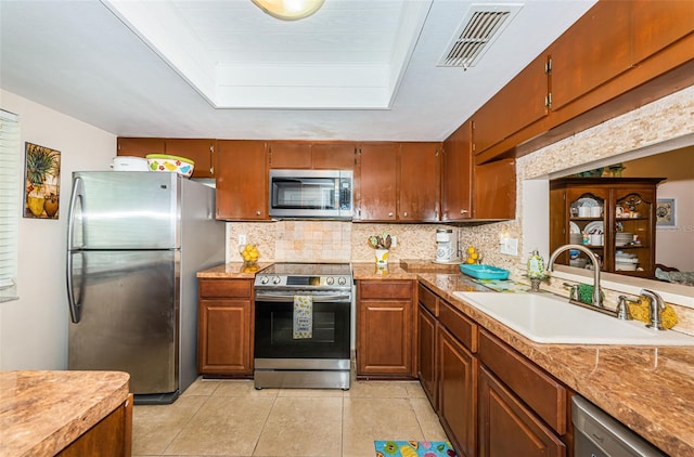 kitchen with a sink, visible vents, backsplash, appliances with stainless steel finishes, and light tile patterned floors