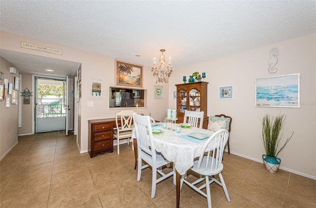 dining area featuring baseboards, a textured ceiling, a notable chandelier, and light tile patterned floors