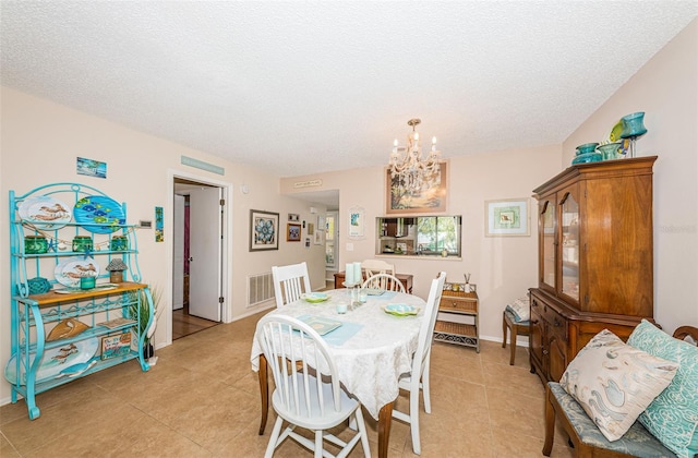 dining space featuring visible vents, an inviting chandelier, a textured ceiling, and light tile patterned floors