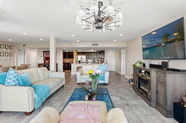 living room featuring recessed lighting, visible vents, light wood-style floors, and a notable chandelier