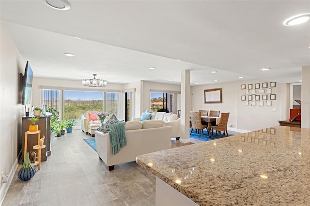 living room with recessed lighting, baseboards, a chandelier, and light wood-type flooring