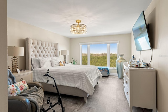 bedroom with an inviting chandelier, baseboards, and wood finished floors