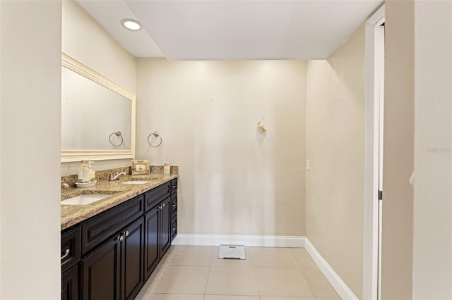 full bathroom with baseboards, double vanity, a sink, and tile patterned flooring
