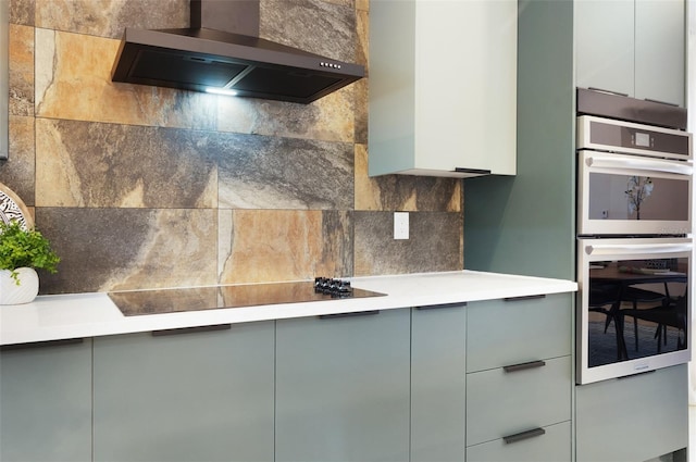 1320 Coral Way S, Saint Petersburg, FL 33705 - kitchen featuring wall chimney exhaust hood, stainless steel double oven, gray cabinets, backsplash, and modern cabinets
