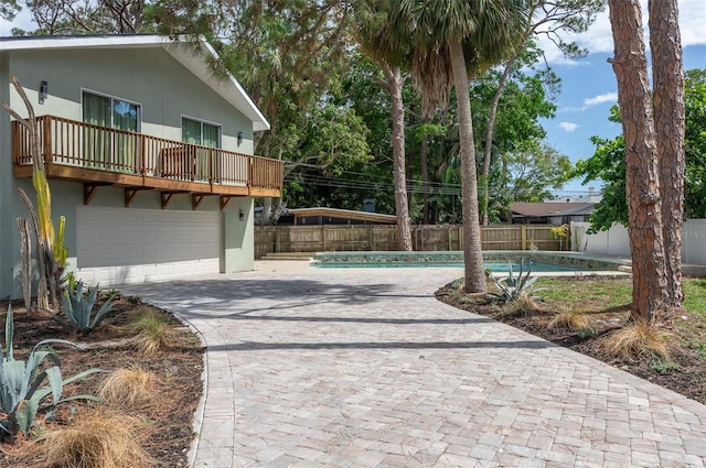 1320 Coral Way S, Saint Petersburg, FL 33705 - view of front facade featuring decorative driveway, stucco siding, a balcony, a fenced backyard, and a garage