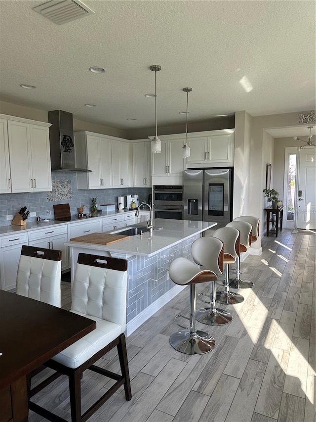 1904 146th Ter E, Parrish, FL 34219 - kitchen with visible vents, wall chimney exhaust hood, a textured ceiling, a sink, and appliances with stainless steel finishes