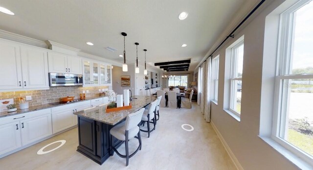 1904 146th Ter E, Parrish, FL 34219 - kitchen featuring baseboards, a kitchen breakfast bar, white cabinetry, stainless steel microwave, and tasteful backsplash