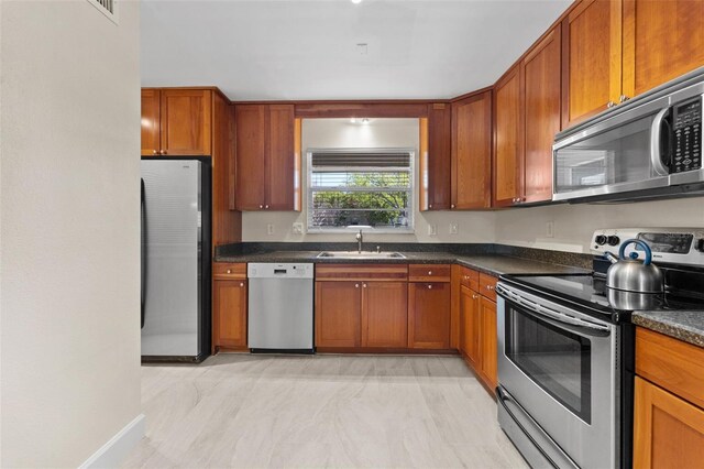 2700 Bayshore Blvd Unit 512, Dunedin, FL 34698 - kitchen featuring appliances with stainless steel finishes, a sink, dark countertops, and brown cabinets