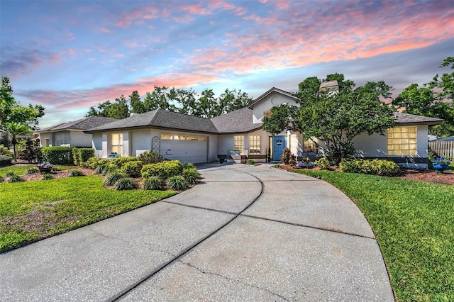view of front facade featuring stucco siding, a lawn, concrete driveway, and an attached garage
