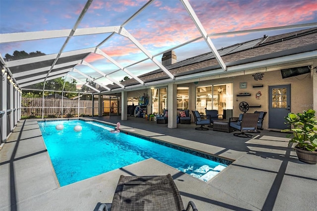 pool at dusk with a fenced in pool, fence, a lanai, outdoor lounge area, and a patio area