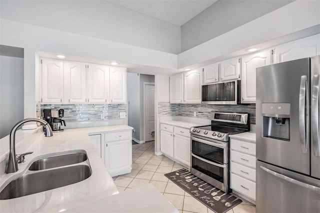 kitchen featuring white cabinets, light tile patterned floors, appliances with stainless steel finishes, and a sink