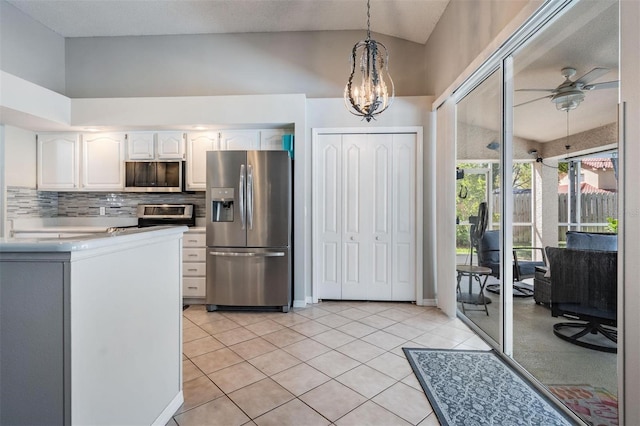 kitchen with light tile patterned floors, stainless steel appliances, hanging light fixtures, white cabinetry, and backsplash