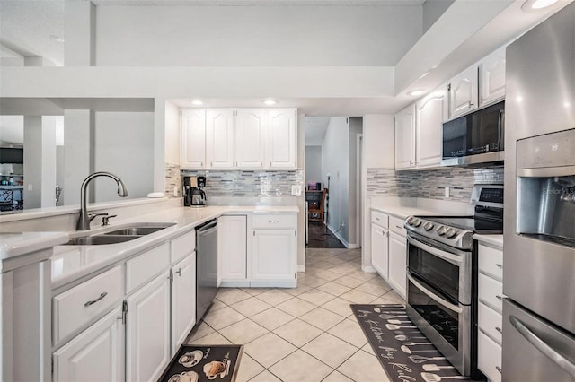 kitchen with light countertops, light tile patterned floors, white cabinets, stainless steel appliances, and a sink