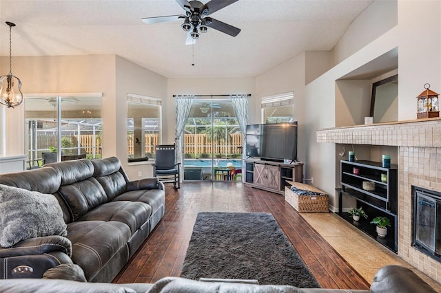 living room with ceiling fan, vaulted ceiling, wood finished floors, and a tile fireplace