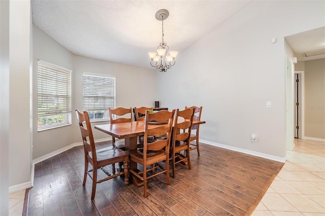 dining area featuring a notable chandelier, vaulted ceiling, baseboards, and wood finished floors