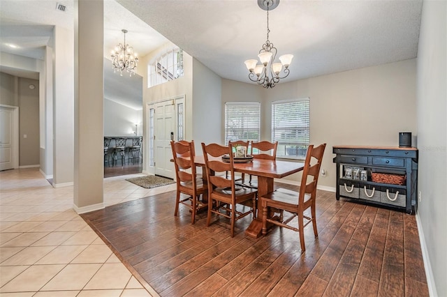 dining area with visible vents, wood finished floors, baseboards, and a chandelier