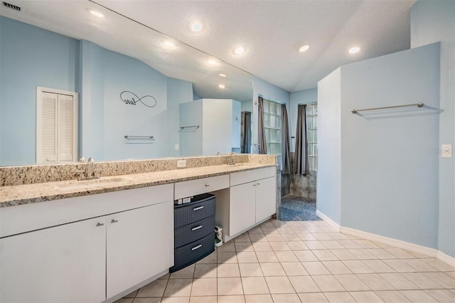 bathroom with tile patterned flooring, lofted ceiling, double vanity, and a sink