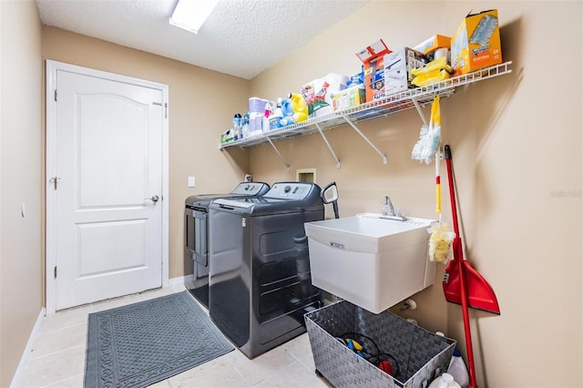 laundry room with light tile patterned floors, laundry area, washer and dryer, a textured ceiling, and a sink