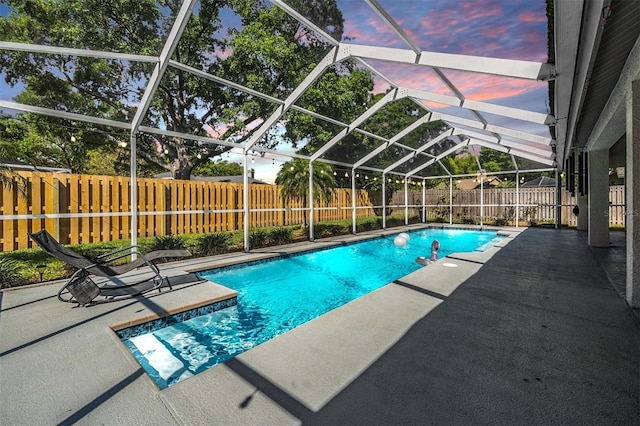 pool at dusk with a patio, a fenced backyard, a fenced in pool, and a lanai