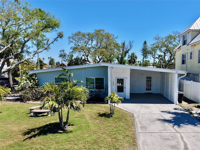 view of front facade with an attached carport, fence, concrete driveway, a front yard, and stucco siding