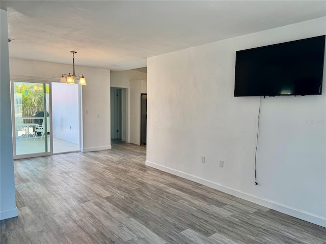unfurnished living room featuring light wood finished floors, a notable chandelier, and baseboards