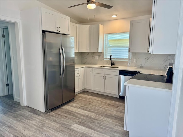 kitchen featuring ceiling fan, appliances with stainless steel finishes, light wood-style floors, white cabinets, and a sink
