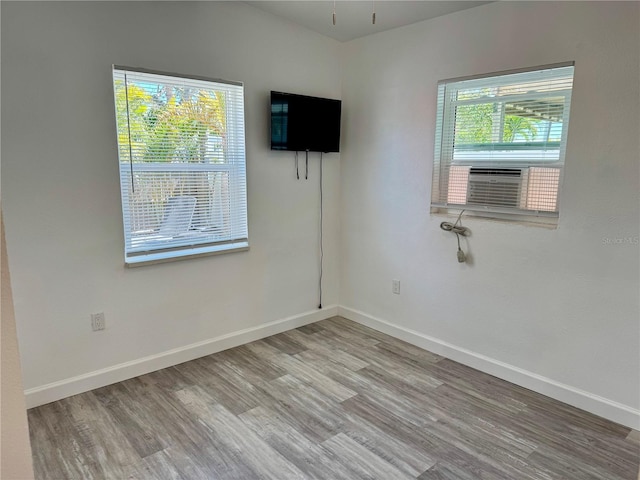 empty room with cooling unit, wood finished floors, and baseboards