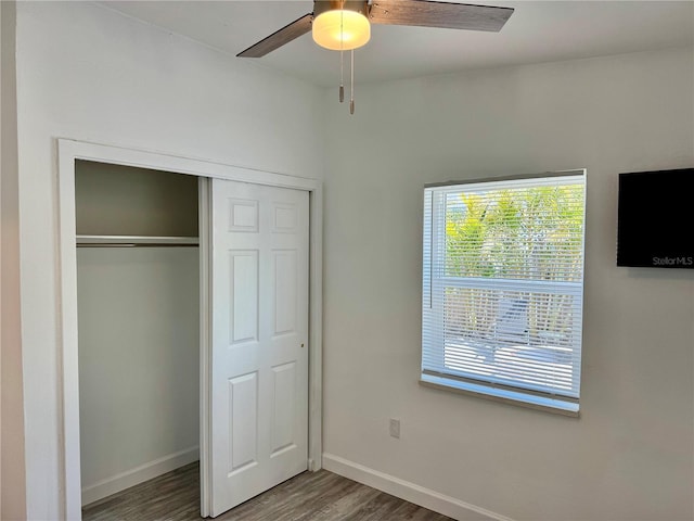 unfurnished bedroom with a closet, a ceiling fan, baseboards, and wood finished floors