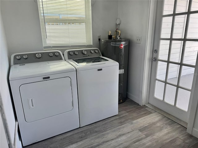 laundry room featuring water heater, washing machine and dryer, a wealth of natural light, and light wood-style floors