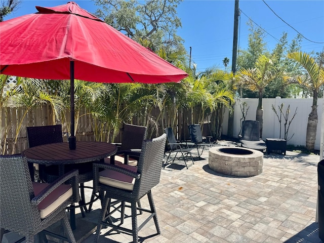 view of patio / terrace with a fire pit, a fenced backyard, and outdoor dining space