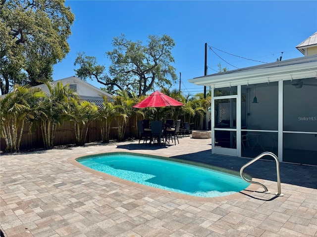 view of pool with outdoor dining space, a patio, fence, a fenced in pool, and a sunroom